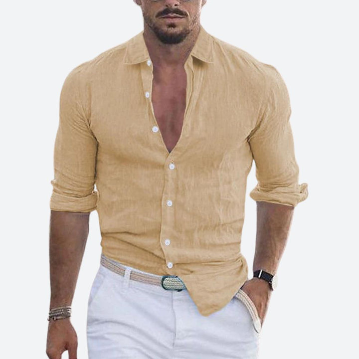 Chemise beige sable portée par un homme, col ouvert, manches retroussées, avec pantalon blanc et ceinture tressée. 8