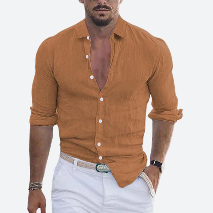 Chemise caramel portée par un homme, col ouvert, manches retroussées, associée à un pantalon blanc et une ceinture tressée. 3