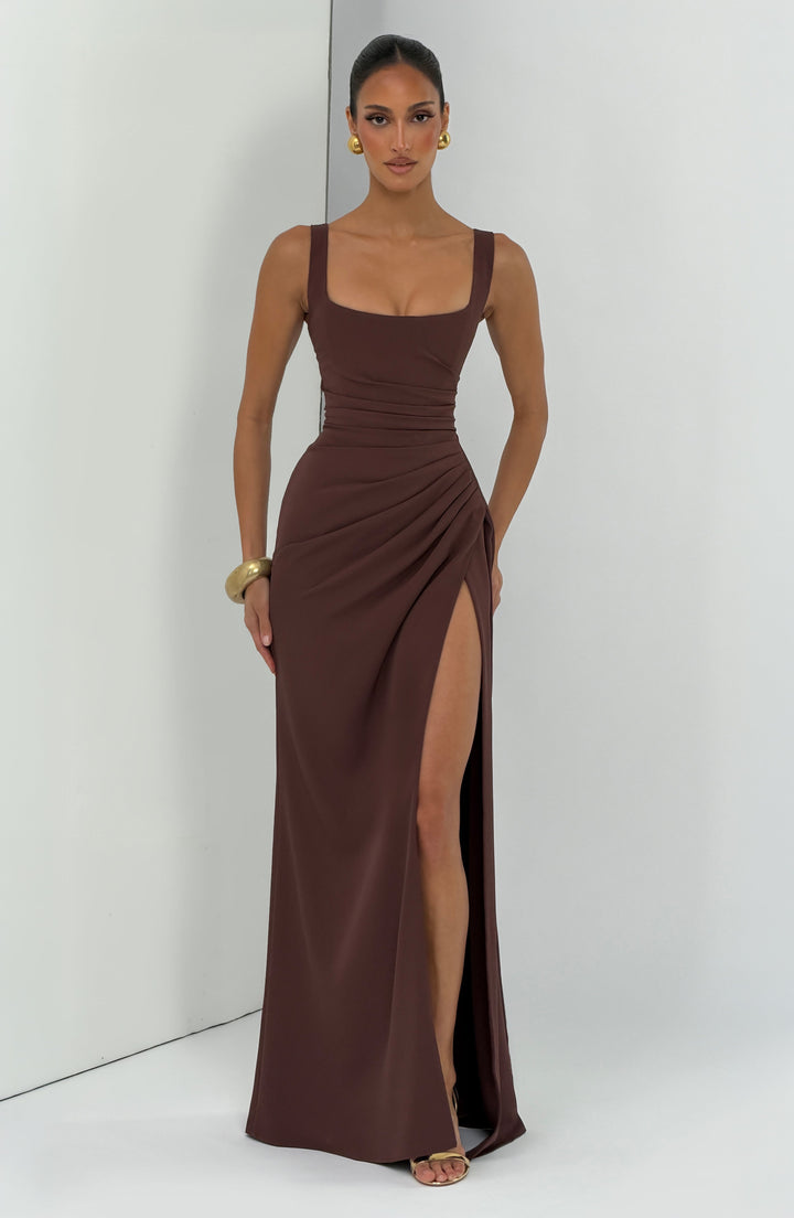 Robe marron chocolat portée de face dans un décor de studio clair avec angle de mur, fente haute dégageant la jambe. 8