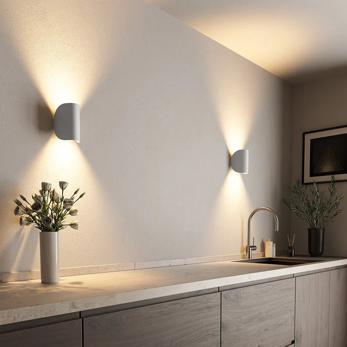 Deux appliques blanches en demi-cylindre dans une cuisine moderne, avec faisceaux de lumière chaude vers le haut et vers le bas. 4