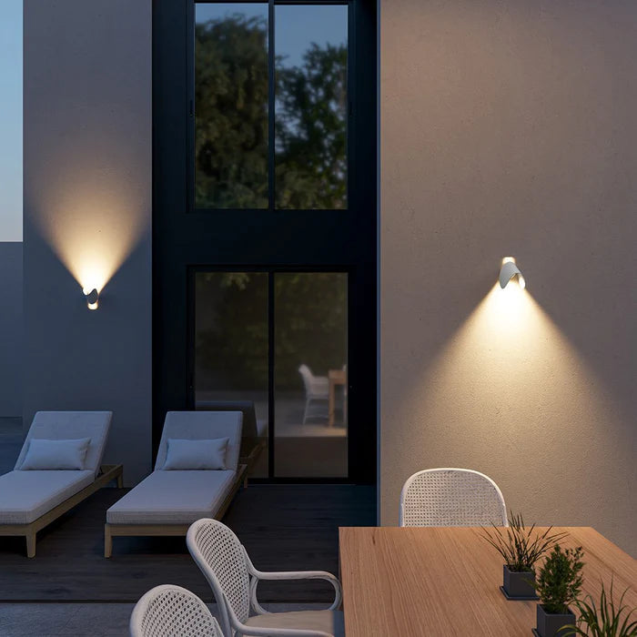 Appliques blanches orientées vers le bas sur le mur d'une terrasse le soir, près de transats et d'une table en bois. 5