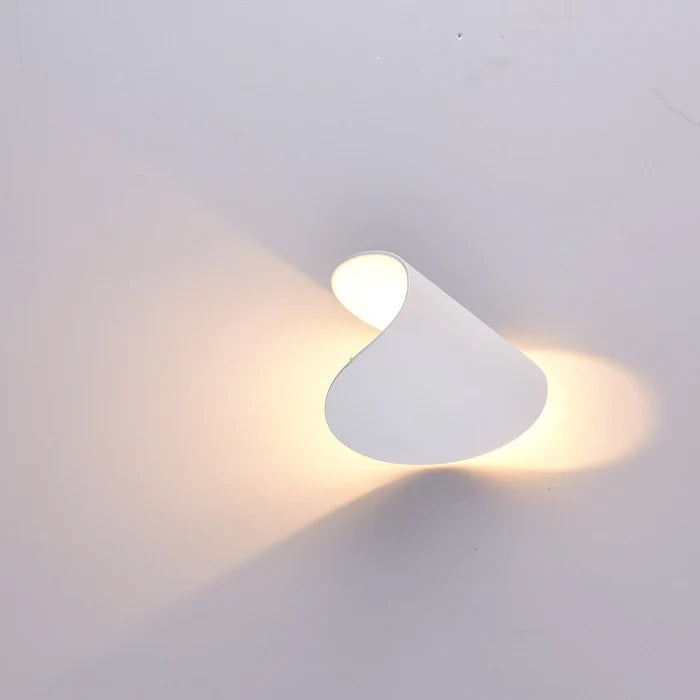 Applique blanche tournée de côté, deux faisceaux de lumière chaude se projetant de part et d'autre sur le mur. 17