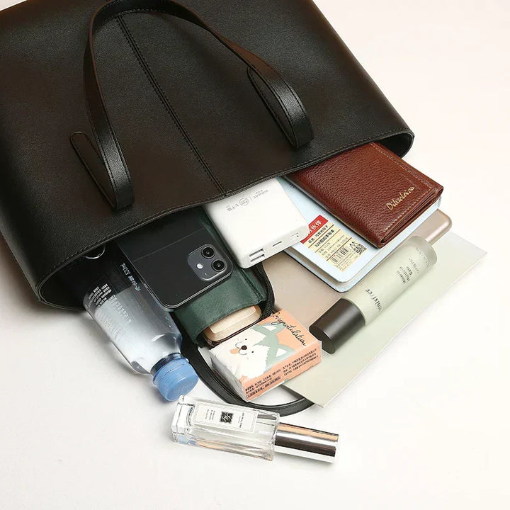 Sac noir renversé laissant sortir téléphone, portefeuille, bouteille d'eau, parfum, cahier et autres affaires personnelles 6
