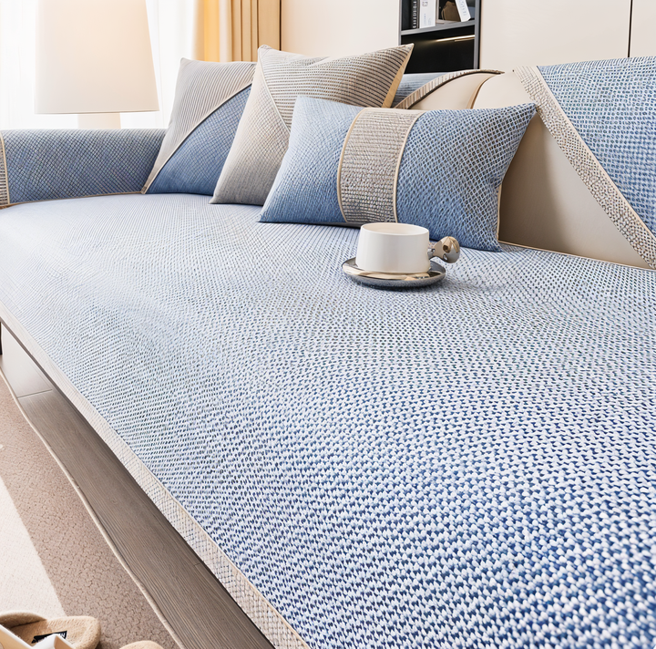 Housse bleu clair au tissu texturé recouvrant l'assise du canapé, coordonnée à des coussins bleu et beige. 7
