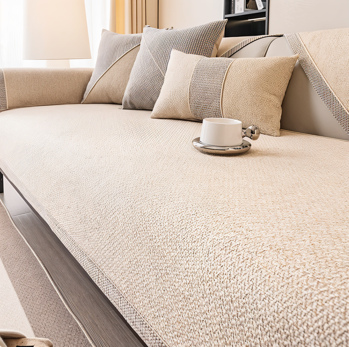 Housse crème au tissu doux et épais sur le canapé, avec coussins crème et gris et tasse blanche sur l'assise. 9
