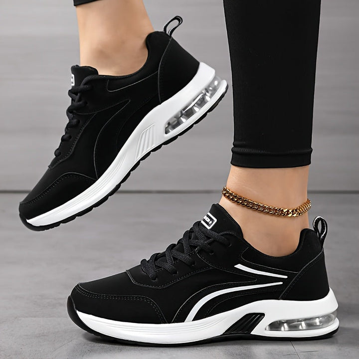 Baskets noires portées, vues de profil avec lacets, languette de tirage au talon et semelle blanche à bulle d'air transparente. 3