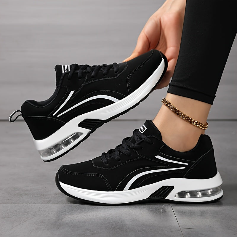 Baskets noires à semelle blanche avec coussin d'air visible, portées avec un legging noir, l'une soulevée pour montrer le profil. 1