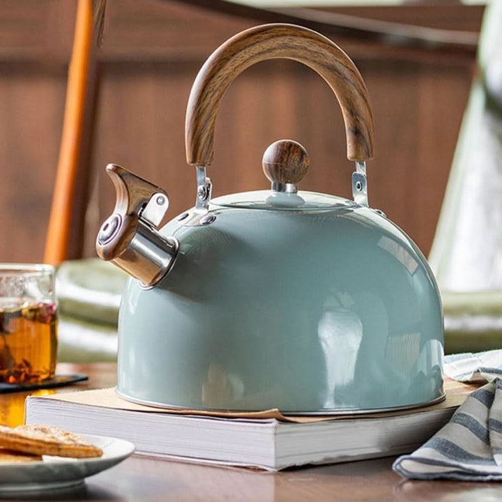 Bouilloire vert-gris posée sur un livre, près d'un verre de thé et de biscuits 2