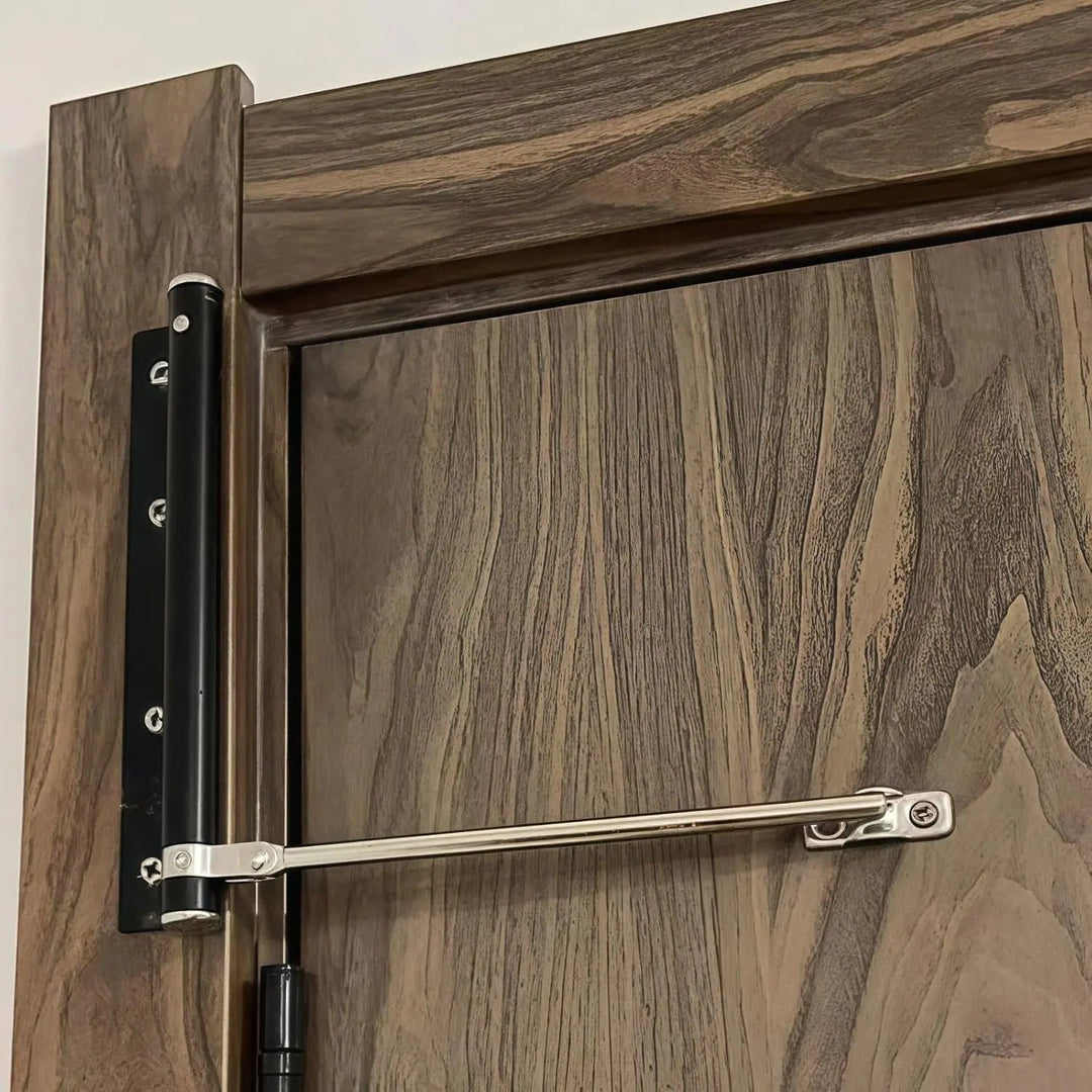 Ferme-porte au corps noir et bras argenté, installé sur une porte en bois foncé 3