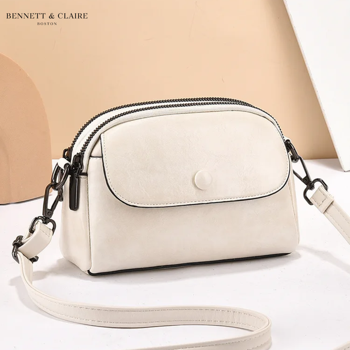 Sac bandoulière blanc crème à rabat avec bouton pression, double fermeture zippée et liseré noir, bandoulière fine posée devant. 4