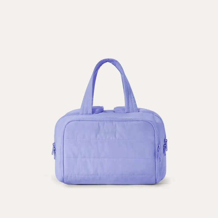 Trousse matelassée de face dans un coloris bleu lavande, avec anses souples et fermetures éclair assorties. 13