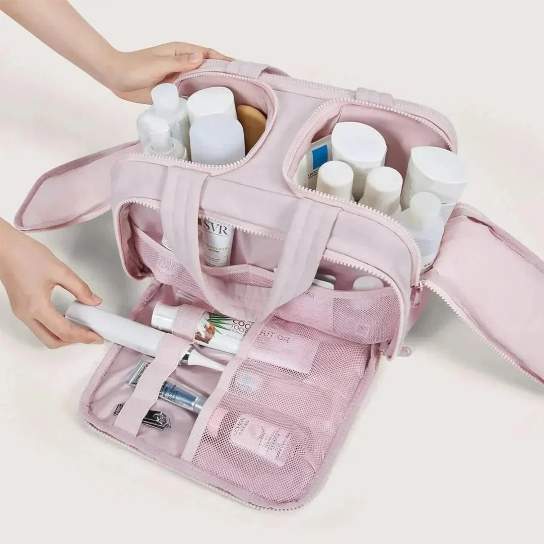 Trousse rose ouverte sur ses deux compartiments supérieurs et la poche à filet, remplie de flacons, d'une brosse à dents et de soins. 3