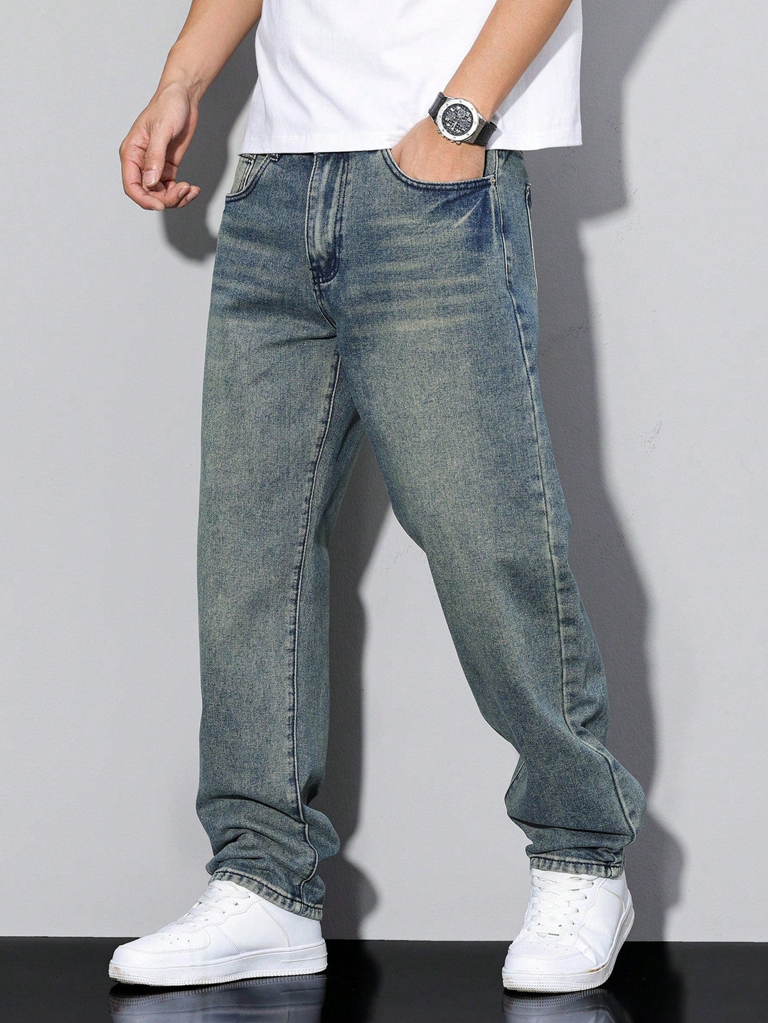 Jean baggy bleu vintage aux reflets verdâtres et à l'aspect usé, porté avec un t-shirt blanc et des baskets blanches. 10
