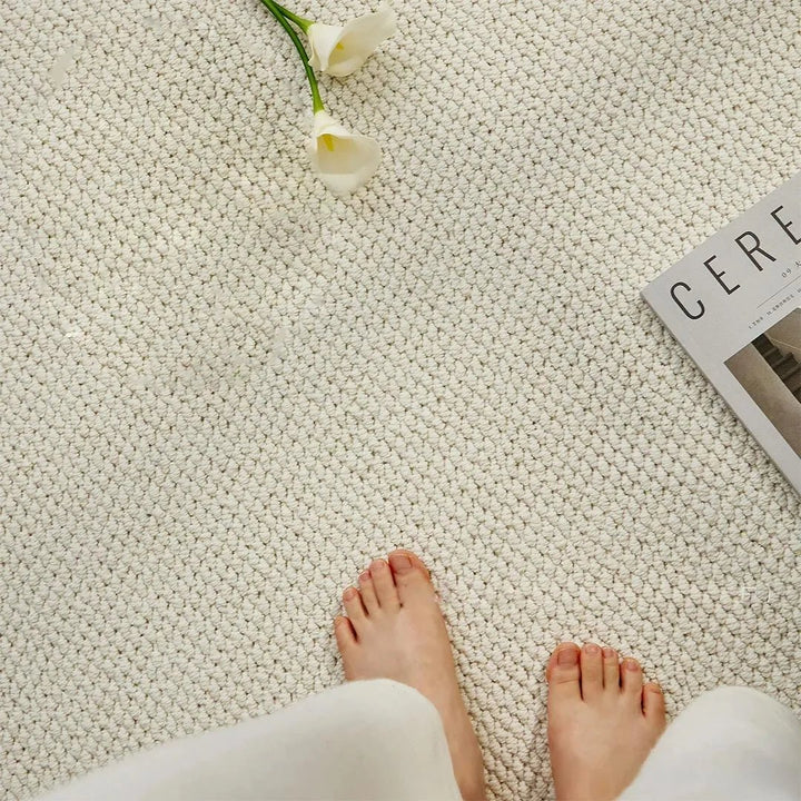 Vue de dessus du tapis crème à poil bouclé avec des pieds nus, une fleur blanche et un magazine 6