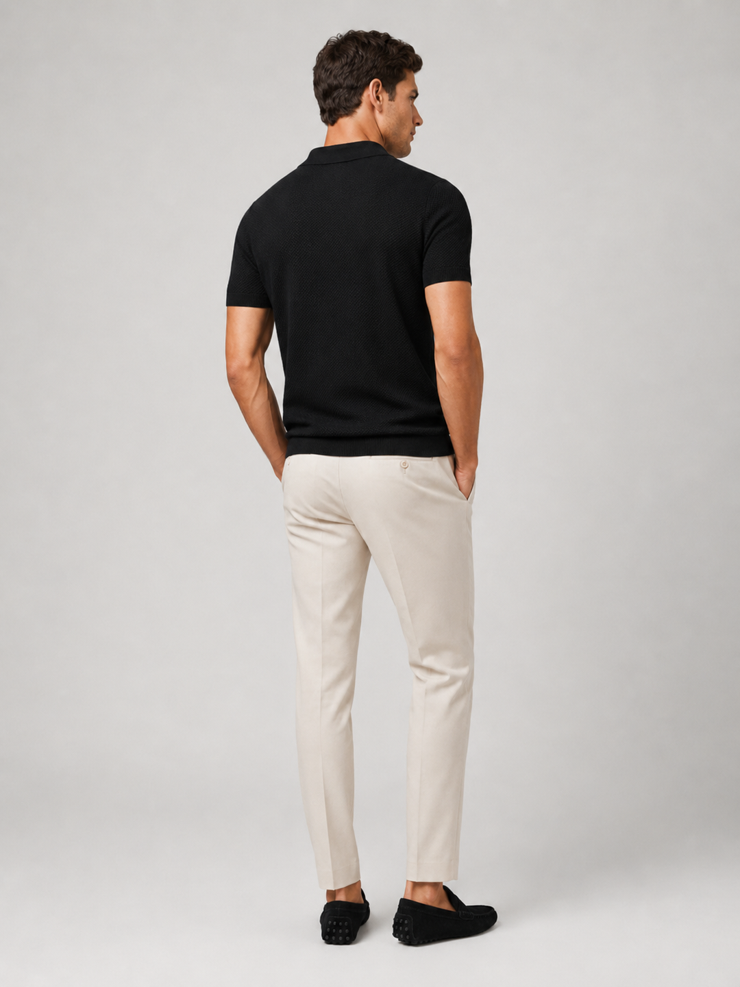 Polo noir vu de dos, homme tourné de côté, pantalon beige et mocassins noirs 9