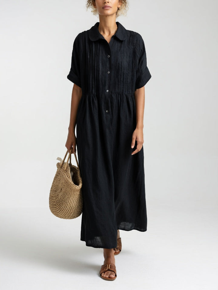 Robe noire portée par une femme, bras le long du corps, panier en paille à la main, boutons visibles sur le devant. 7
