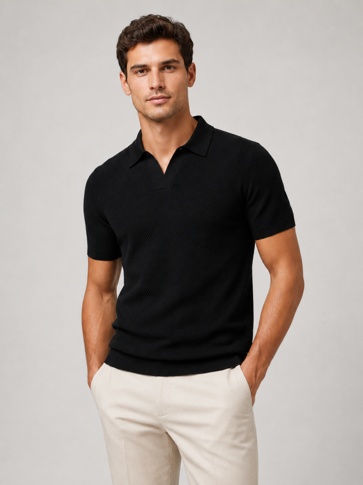 Homme portant le polo noir à col ouvert, vu de face, pantalon beige, fond gris 6