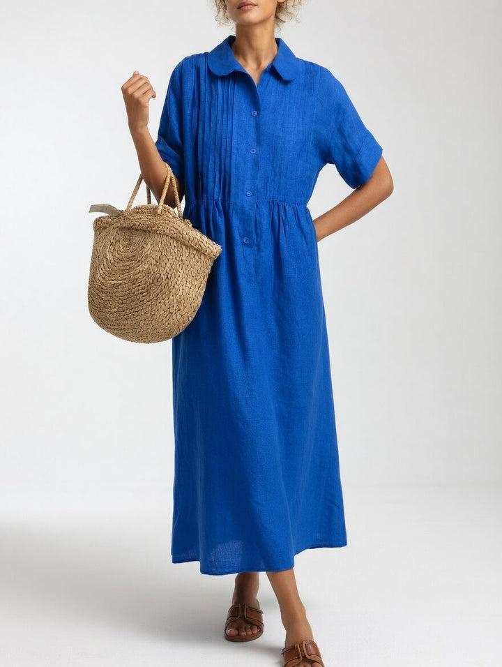 Robe bleu vif portée par une femme, une main sur la hanche, un panier en paille au bras, vue de face. 3