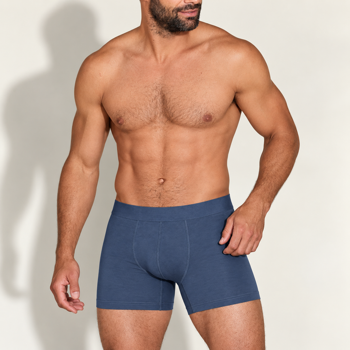 Homme barbu au torse nu portant un boxer bleu denim, vu de face, main posée sur la hanche. 1