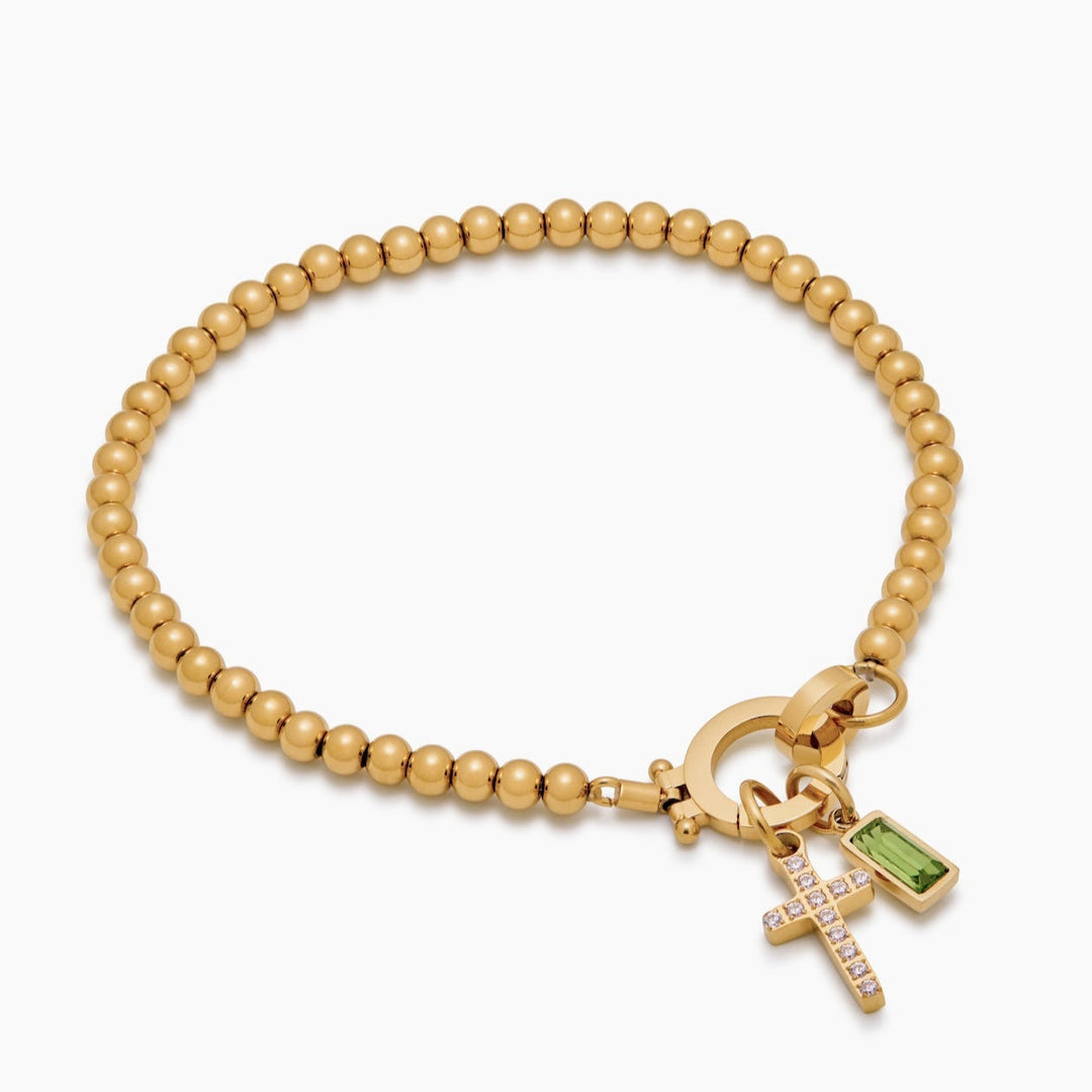 Bracelet de perles dorées vu en perspective, avec croix sertie de strass et pierre verte rectangulaire suspendues au fermoir rond. 8