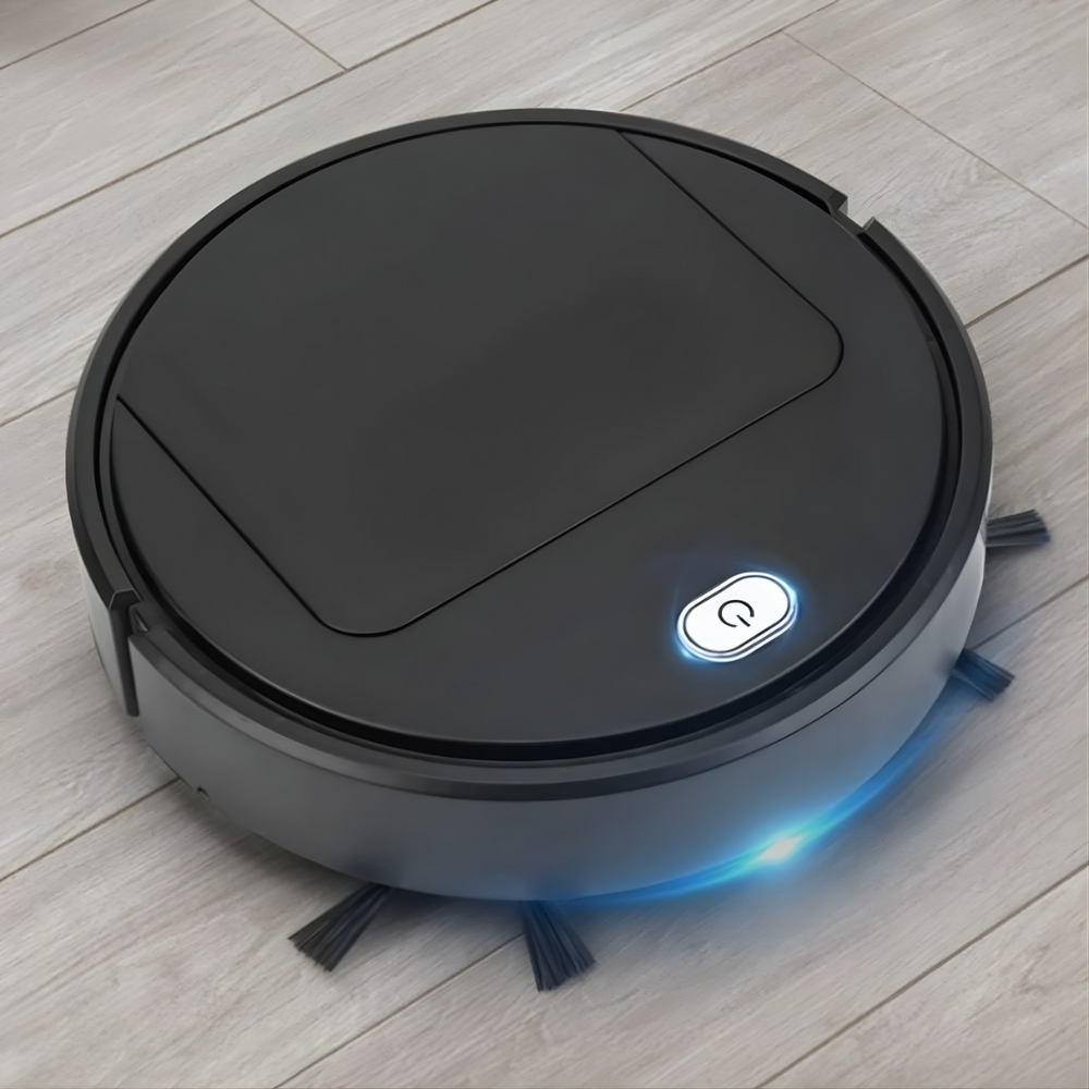 Robot noir posé sur un parquet clair, bouton lumineux et liseré bleu allumés, trois brosses latérales visibles. 2