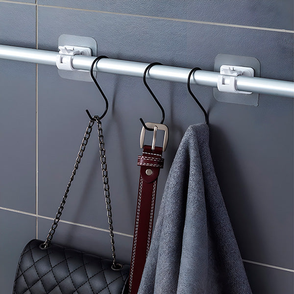 Barre fixée au mur par deux supports blancs, avec crochets en S noirs portant un sac à chaîne, une ceinture et une serviette. 5
