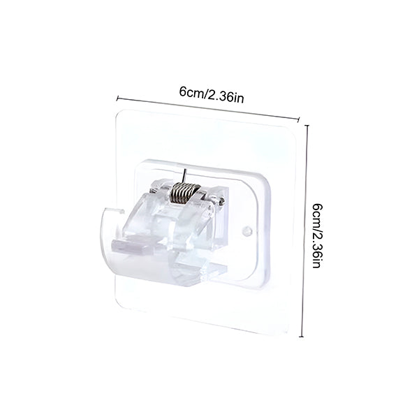 Un support adhésif transparent à ressort avec ses dimensions indiquées, environ 6 cm de côté, sur fond blanc. 10