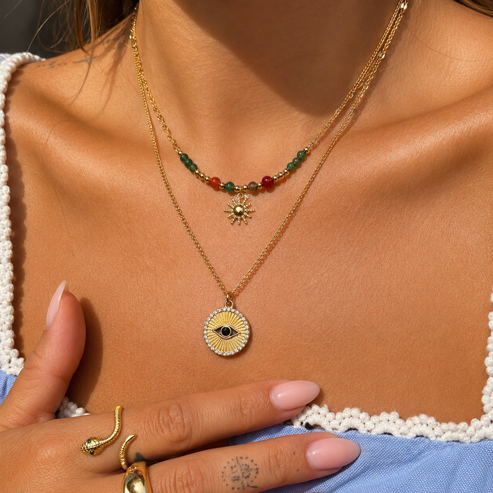 Collier porté au cou par une femme, superposé à un second collier doré avec médaillon œil 3