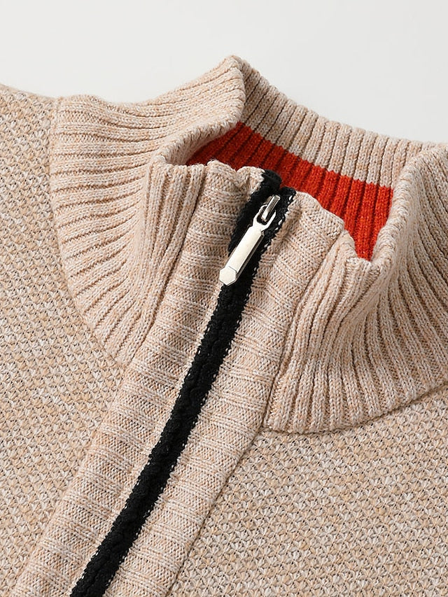 Détail du col montant côtelé beige avec intérieur orange et tirette métallique du zip noir. 9