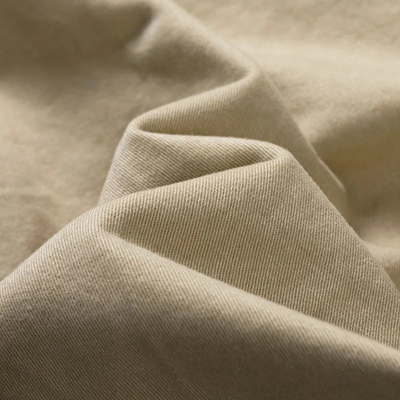 Gros plan sur le tissu beige en sergé, souple et plissé, montrant le grain diagonal de la matière. 8