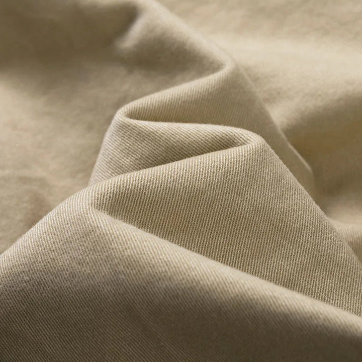 Gros plan sur le tissu beige en sergé, souple et plissé, montrant le grain diagonal de la matière. 8