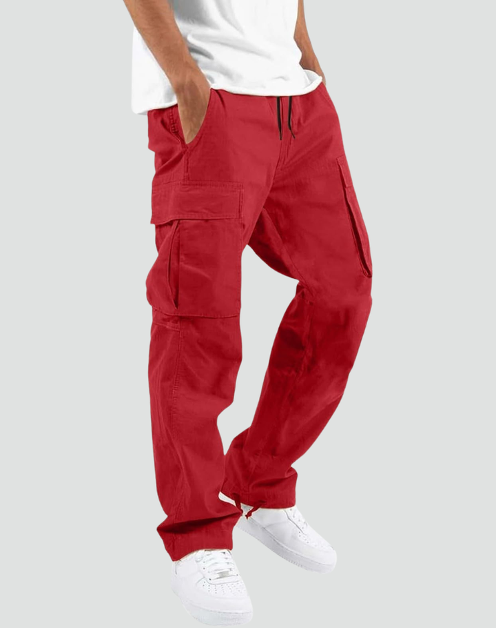 Pantalon cargo rouge porté par un modèle avec t-shirt blanc et baskets blanches, sur fond gris clair, vue de trois quarts. 10