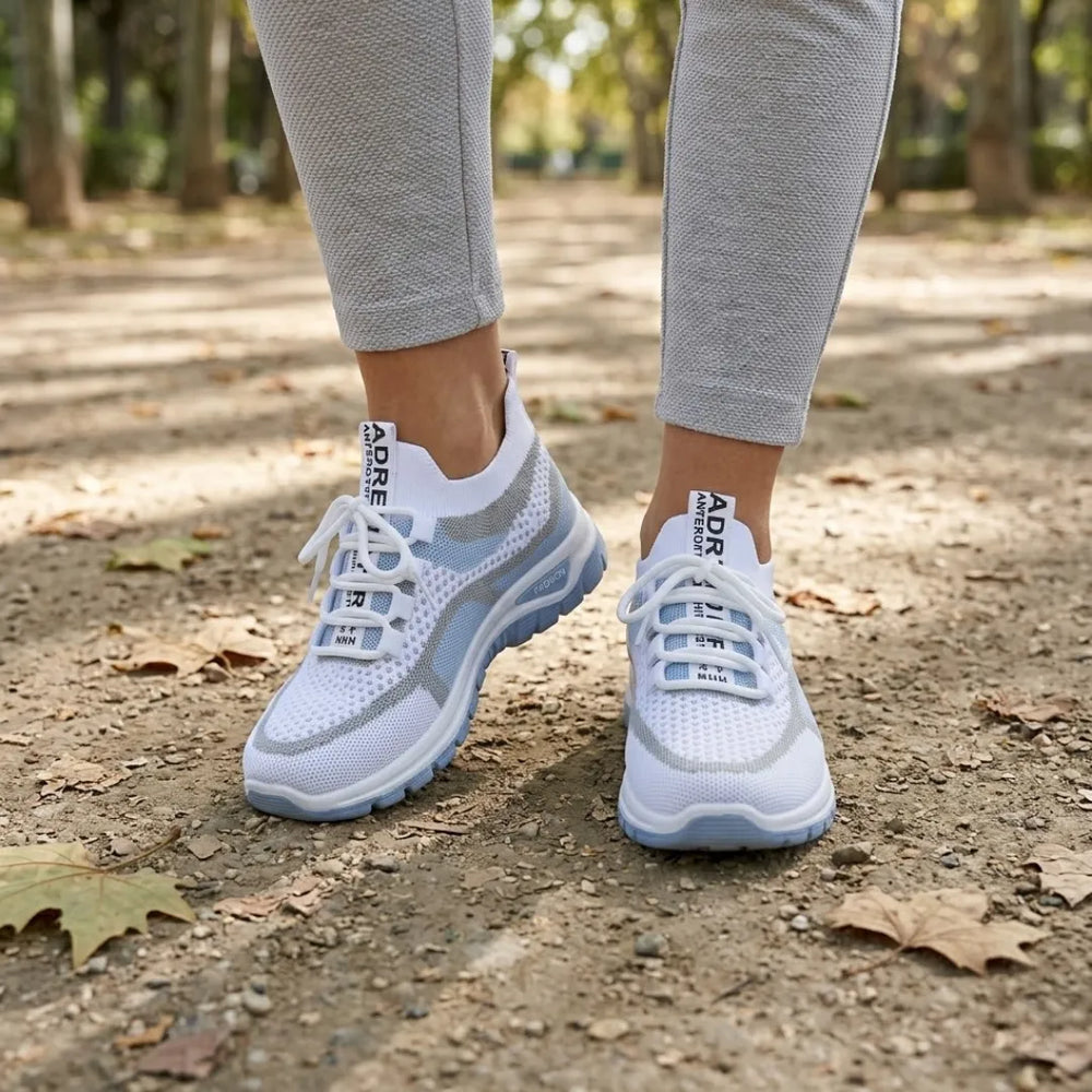 Paire de baskets blanches et bleu clair portée par une femme en legging gris, sur un chemin de terre. 2