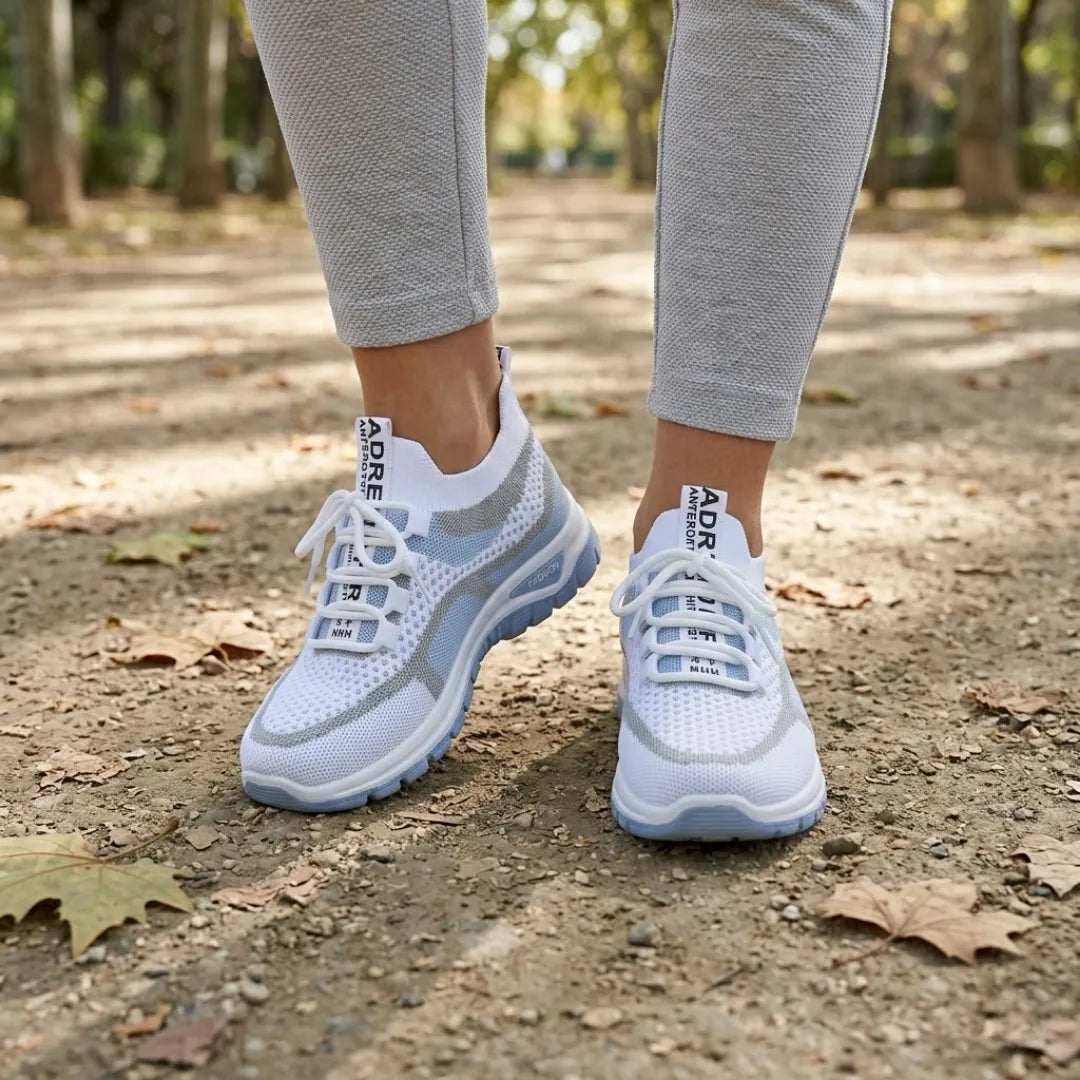 Paire de baskets blanches et bleu clair portée par une femme en legging gris, sur un chemin de terre. 2