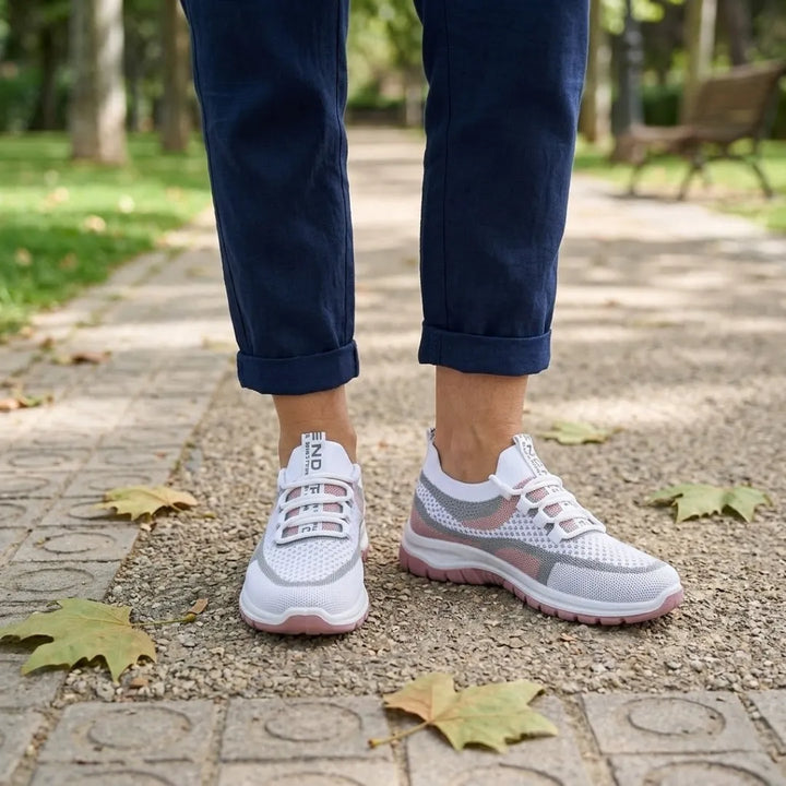 Paire de baskets blanches et roses portée avec un pantalon bleu marine retroussé, sur une allée de parc. 20