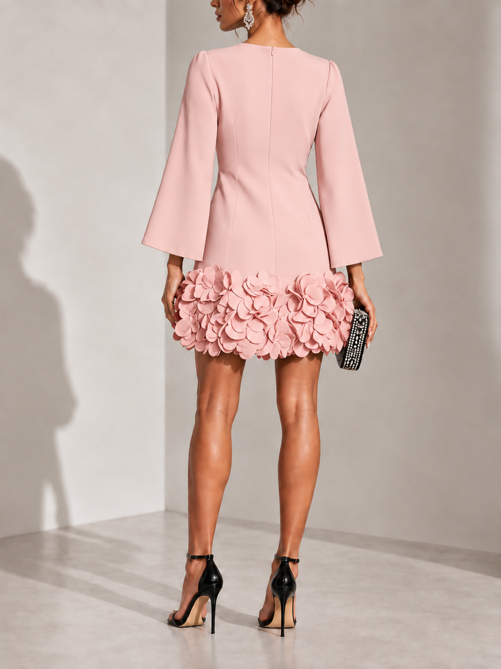 Robe rose poudré vue de dos avec fermeture zippée, manches évasées et ourlet fleuri en relief. 10