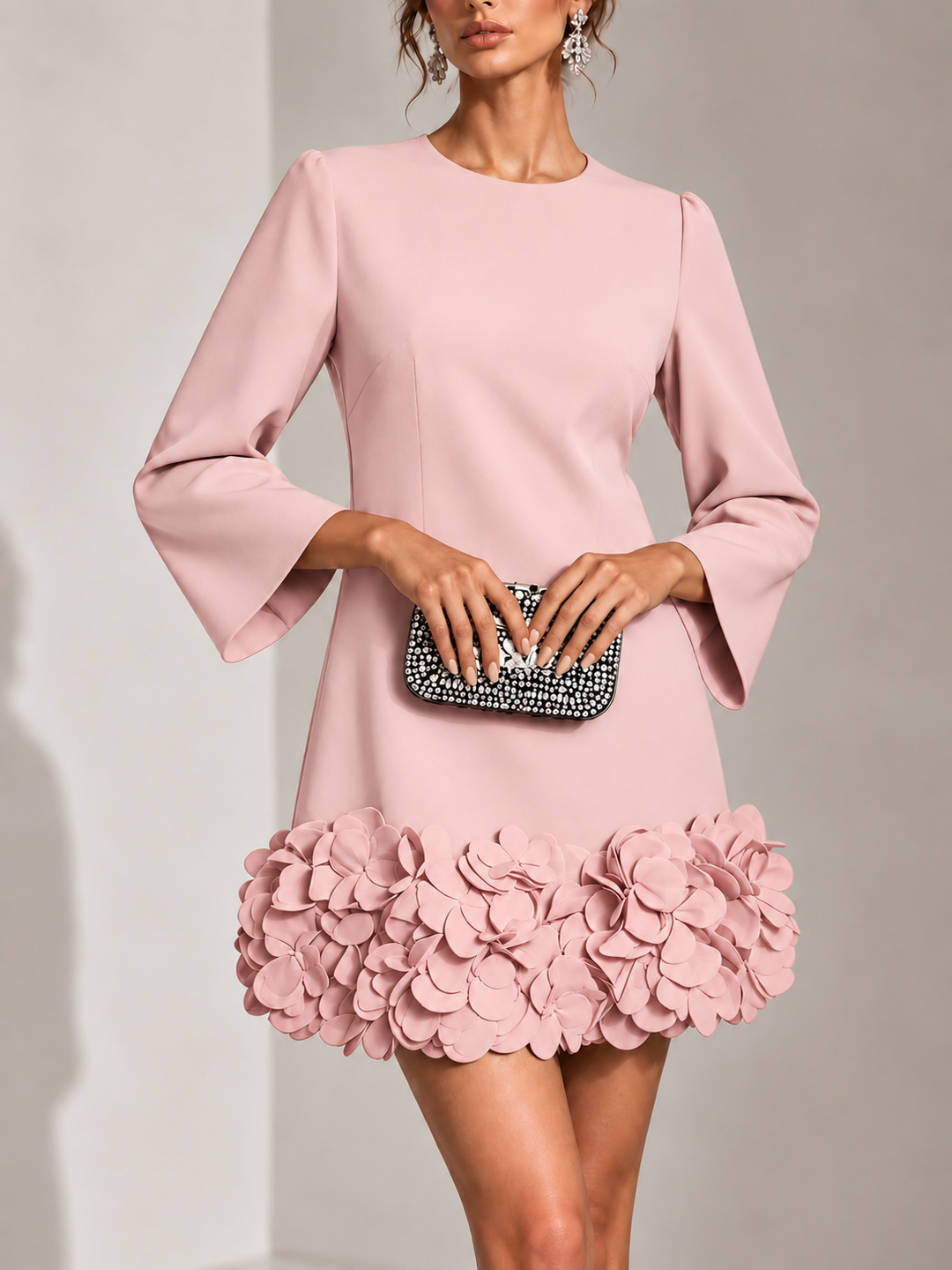 Robe rose poudré portée de face avec une pochette strassée, détail des fleurs 3D volumineuses sur le bas. 9