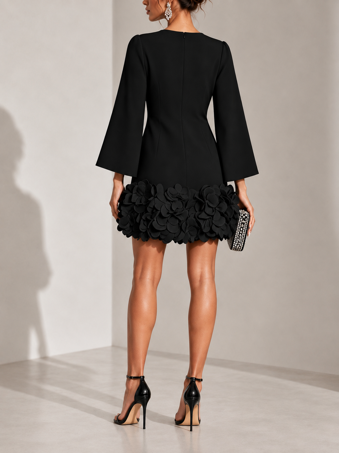 Robe noire vue de dos avec fermeture zippée, manches évasées et bas orné de fleurs en relief. 3