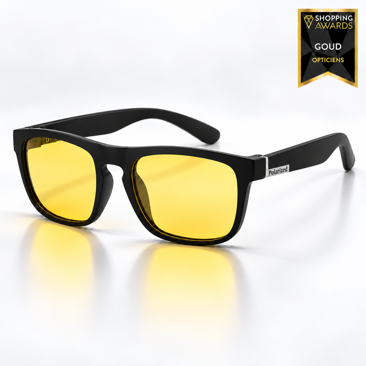 Lunettes à monture noire mate carrée et verres jaunes polarisés, vues de trois quarts sur fond clair avec reflets jaunes au sol. 9