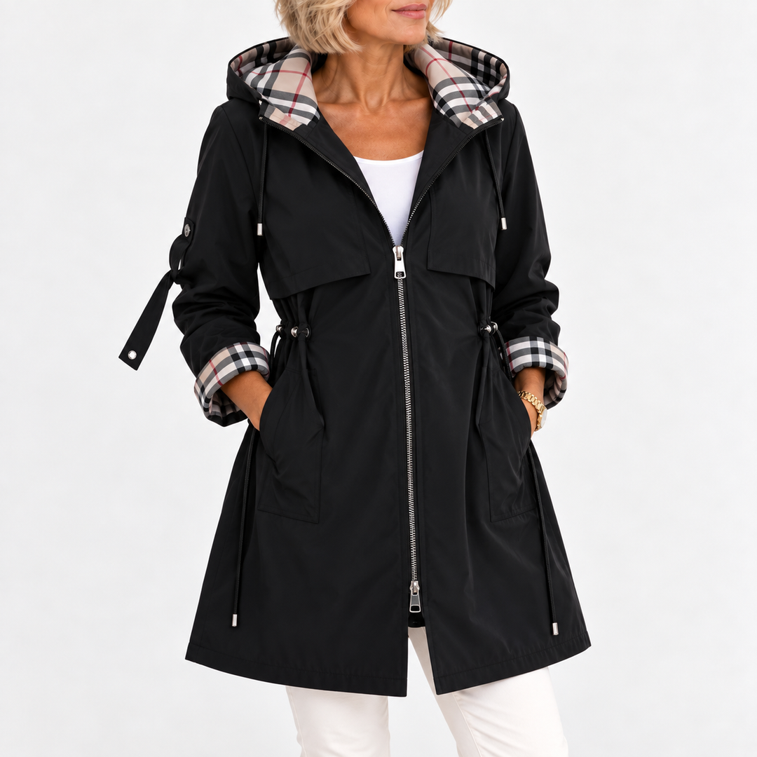 Manteau noir zippé vu de face sur une femme, capuche doublée à carreaux, taille ajustée par cordons, mains dans les poches. 4
