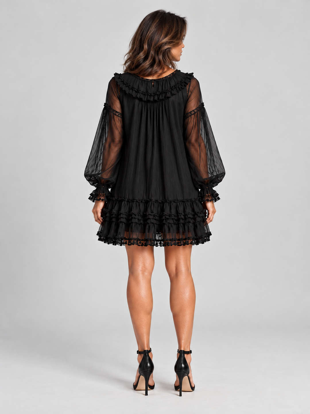 Robe noire portée vue de dos, avec volant autour de l'encolure, manches transparentes et jupe à volants. 4