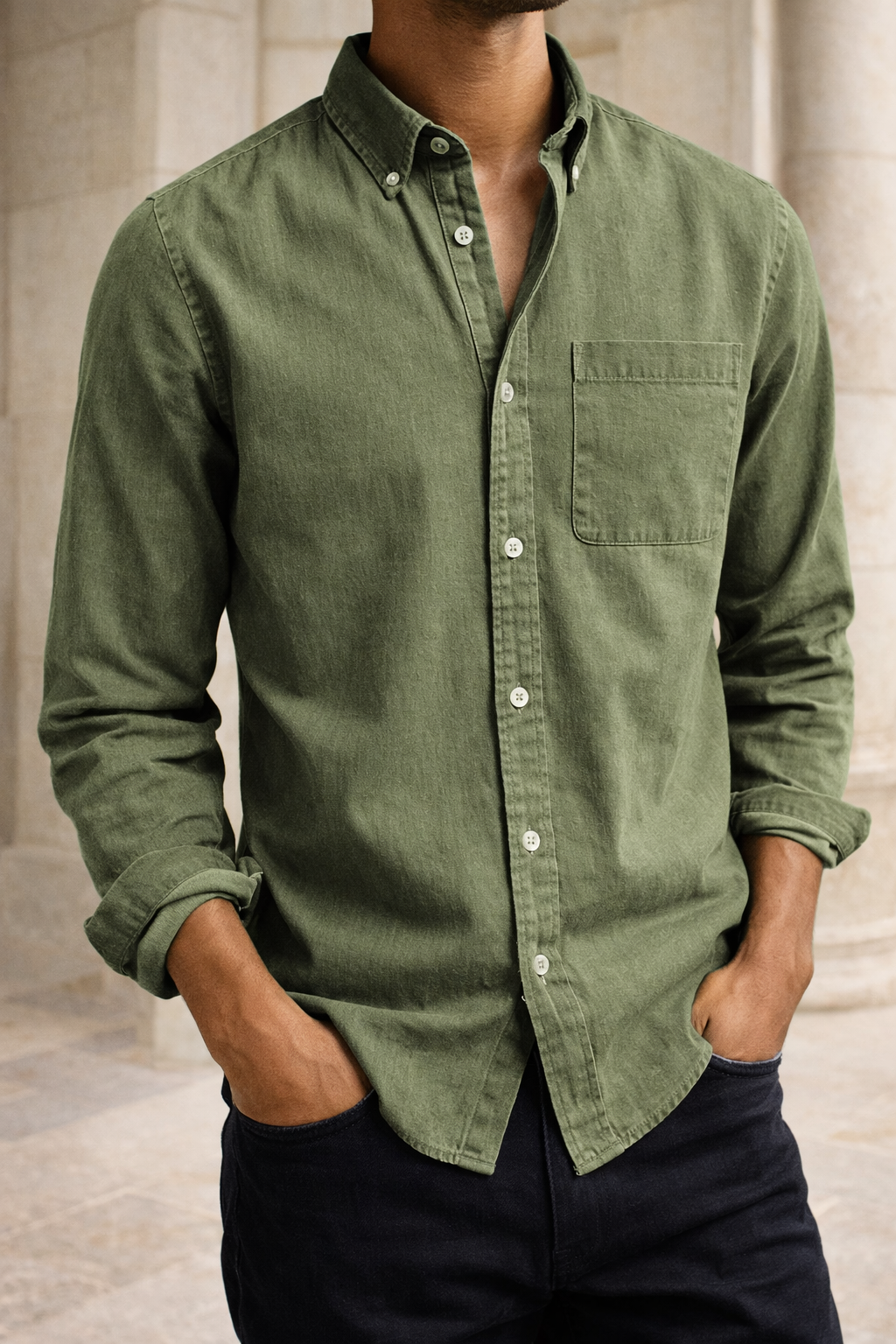 Chemise vert kaki à poche poitrine portée par un modèle, mains dans les poches d'un pantalon foncé, plan rapproché. 4