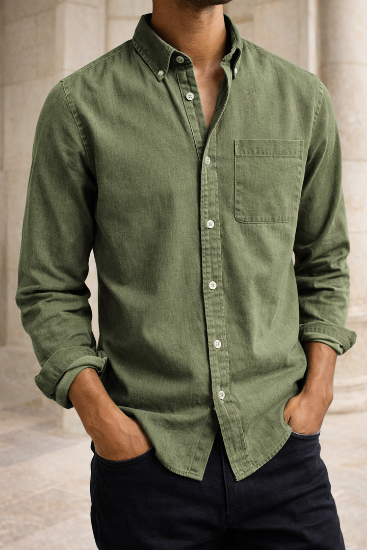 Chemise vert kaki à poche poitrine portée par un modèle, mains dans les poches d'un pantalon foncé, plan rapproché. 4