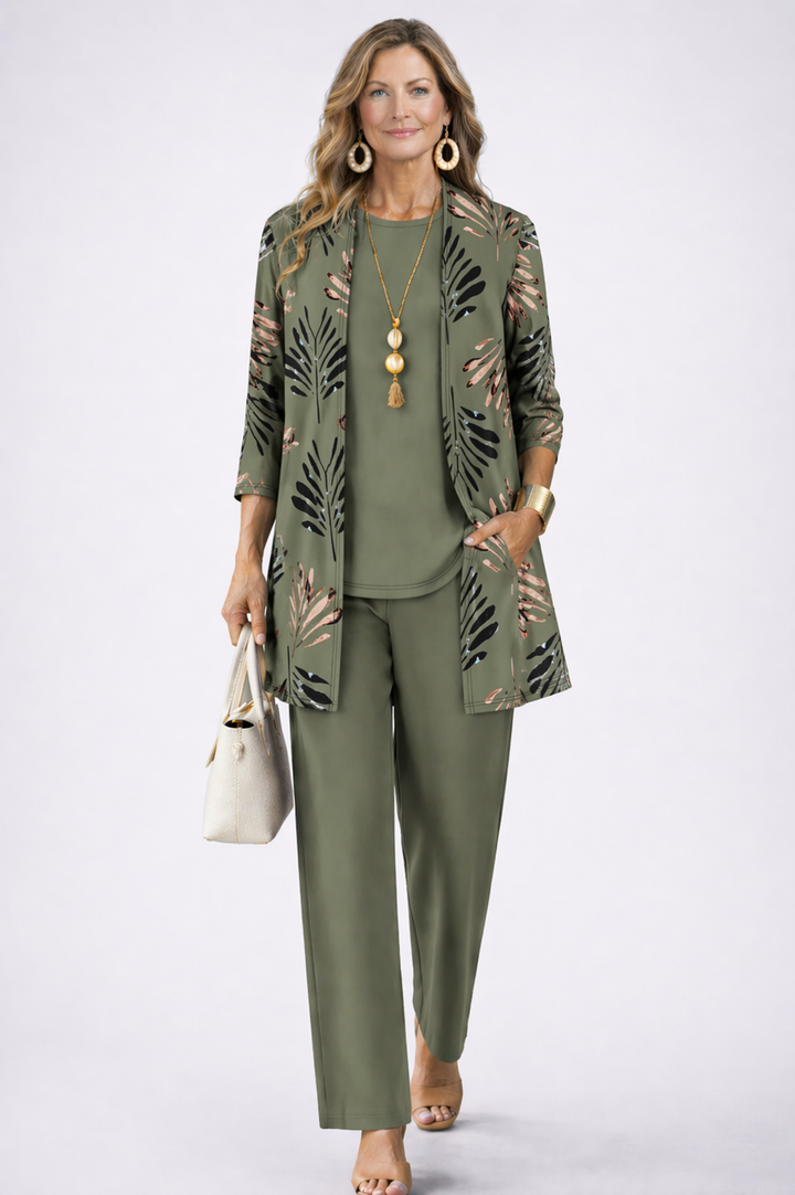 Femme portant l'ensemble vert kaki, cardigan à feuilles de palmier noires et cuivrées, sac crème à la main 1