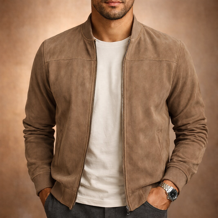 Homme de face portant le blouson beige taupe effet daim zippé ouvert sur un t-shirt blanc, mains dans les poches. 1