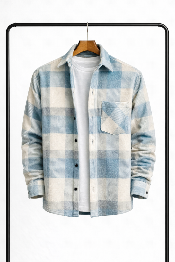 Surchemise à grands carreaux bleu ciel et écru, suspendue ouverte sur un t-shirt blanc, vue de face avec poche poitrine. 1