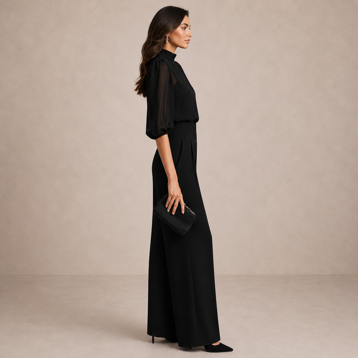 Ensemble noir vu de profil: manches bouffantes en voile, taille haute et jambes larges, pochette à la main 3