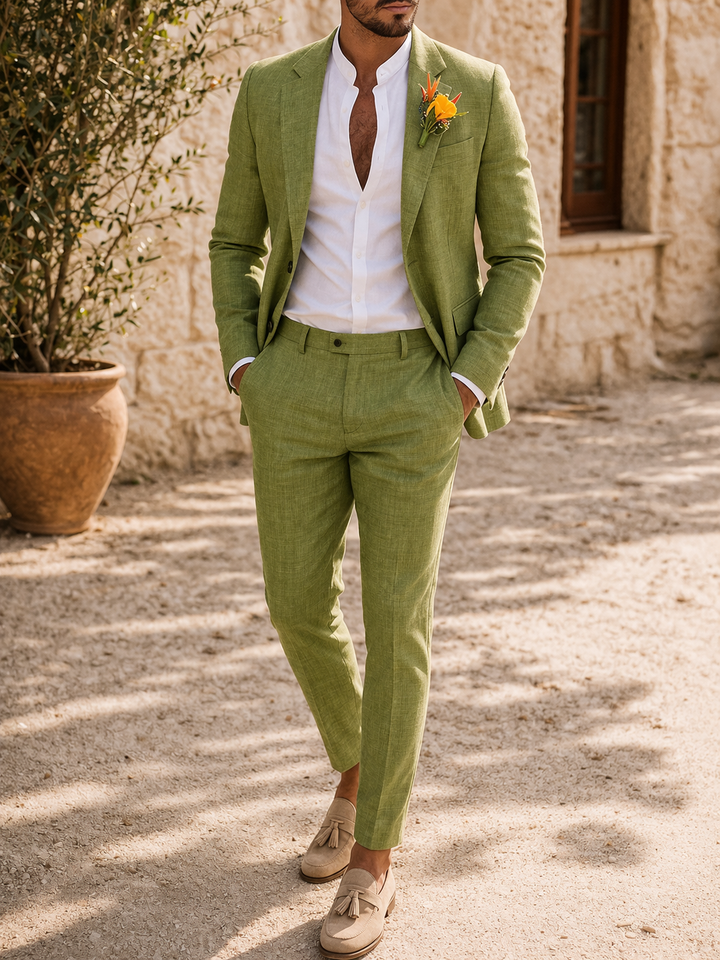 Homme portant le costume deux pièces vert pomme, mains dans les poches, chemise blanche col mao et mocassins beiges à pampilles. 1