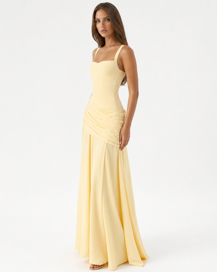 Robe jaune pâle portée par un mannequin de trois quarts, avec le drapé asymétrique sur la hanche et les larges bretelles. 2