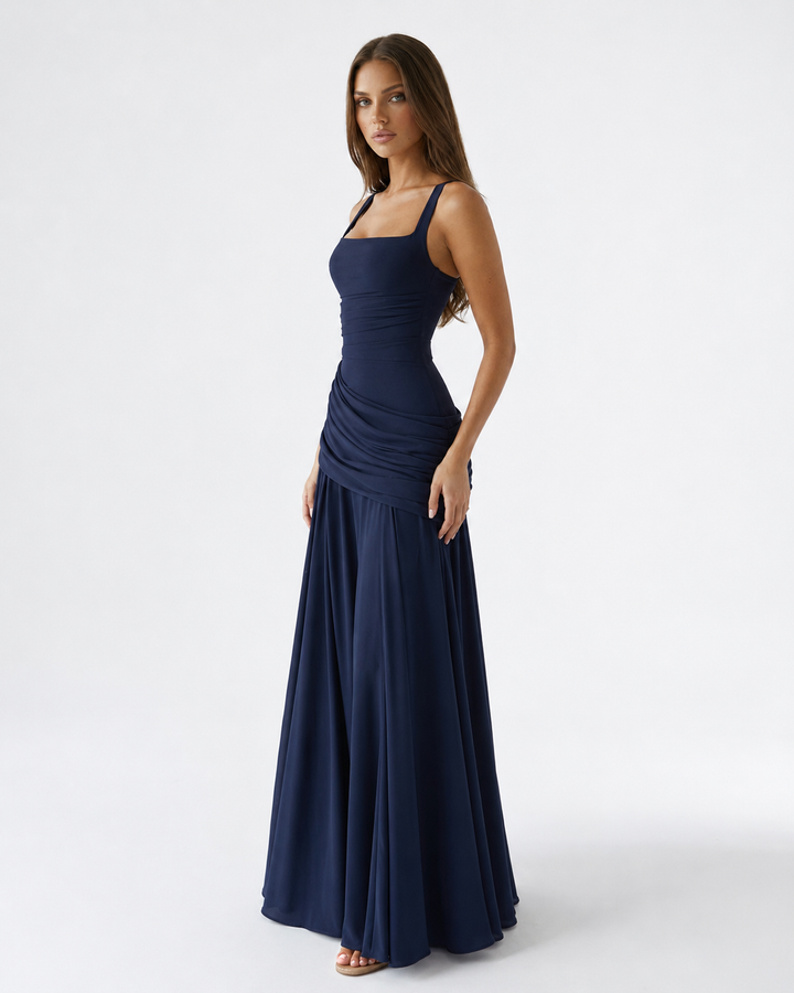 Robe bleu marine vue de trois quarts, encolure carrée, drapé sur la hanche et longue jupe ample. 6